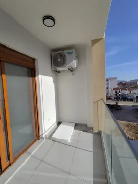 Nenamješten balkon sa staklenom ogradom i klima uređajem na zidu. - image 3