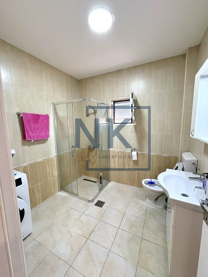 Bathroom equipped with a shower cabin, washbasin, toilet, and washing machine.
