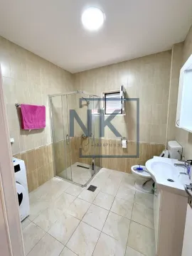 Bathroom equipped with a shower cabin, washbasin, toilet, and washing machine. - image 13