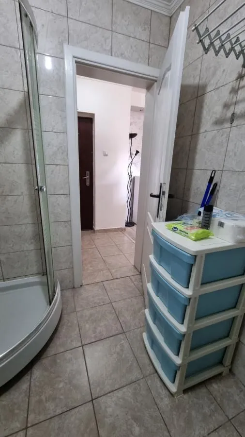 Pogled iz kupatila prema hodniku sa tuš kabinom i pločicama.