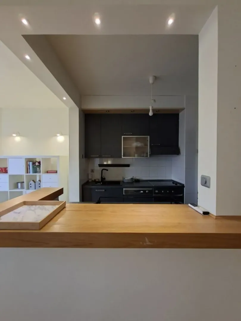 View from the living room towards the kitchen with dark cabinets and a breakfast bar.