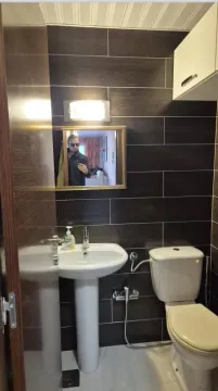 Manje kupatilo sa tamnim zidnim pločicama, umivaonikom i wc šoljom. - image 10