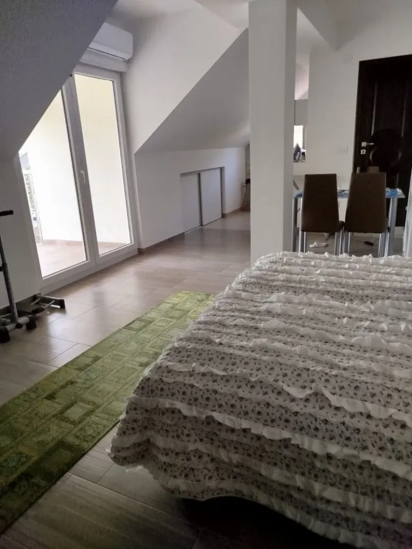 Spavaća soba sa krevetom, krovnim prozorom i izlazom na terasu.
