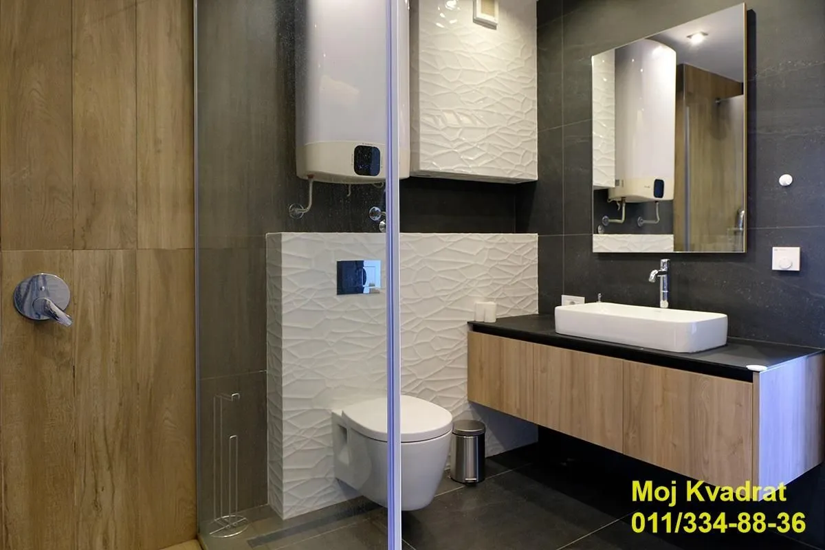 Moderno opremljeno kupatilo sa tuš kabinom, umivaonikom i ugradnom sanitarijom.