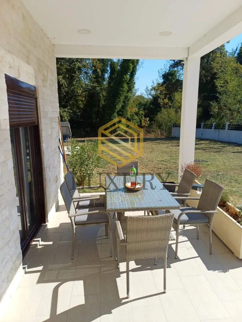 Covered terrace with a dining table and a view of the yard.