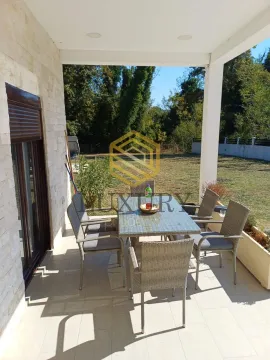 Covered terrace with a dining table and a view of the yard. - image 5