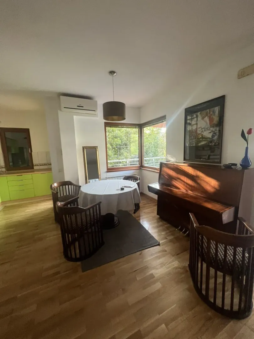 Bright room with a round dining table, chairs, and a piano.