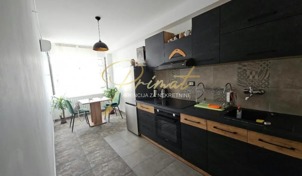 Dark-toned kitchen with a dining area by the window.