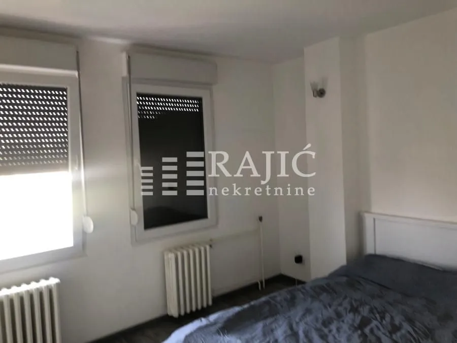 Furnished bedroom with a bed and two windows.