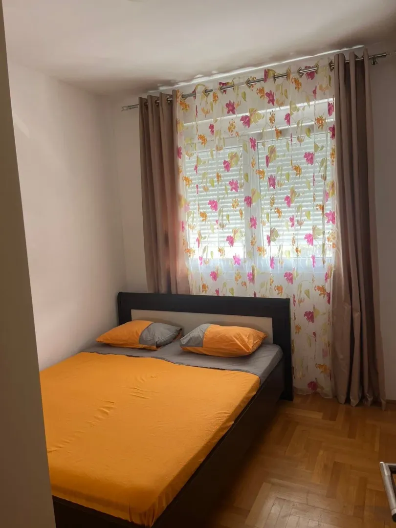 Tidy bedroom with a double bed and a window with curtains.
