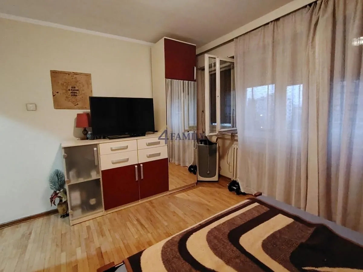 Nameštena spavaća soba sa ormanom, televizorom i krevetom.