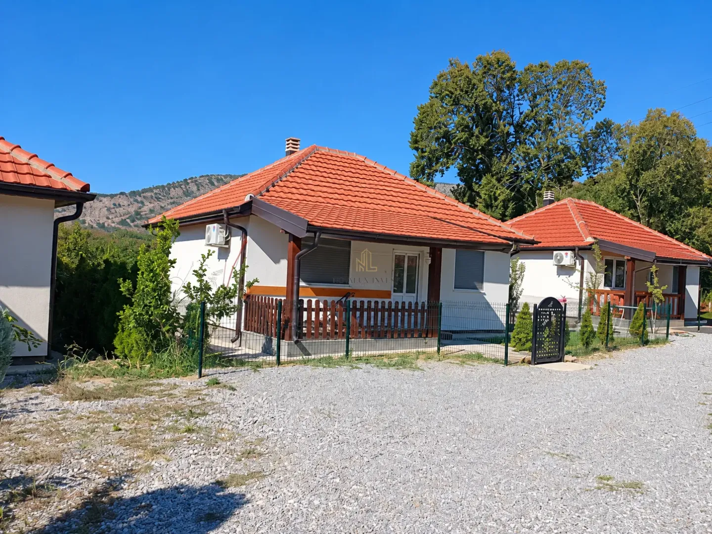 Exterior view of single-story houses with orange roofs and a courtyard.