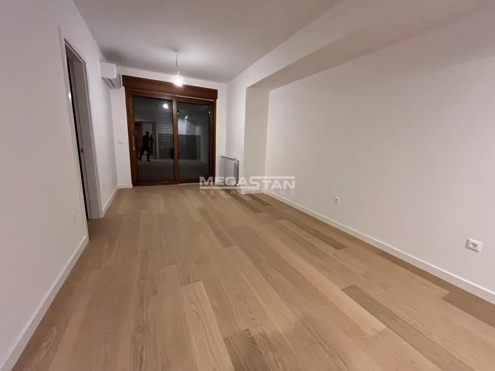 Empty room with wooden flooring and access to the terrace.