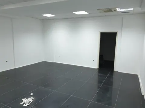 Empty office space with white walls and dark floor tiles. - image 6