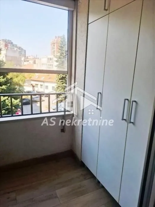 Manji zatvoreni balkon sa ugrađenim plakarom i pogledom na grad.