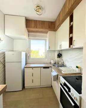 Manja svijetla kuhinja opremljena bijelim elementima i kućnim aparatima. - image 4