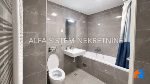 Savremeno opremljeno kupatilo obloženo sivim keramičkim pločicama sa kadom i konzolnom wc šoljom. - image 3