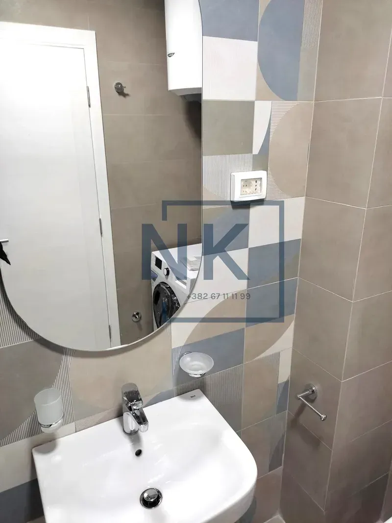 Small bathroom with a washbasin, mirror and patterned tiles.