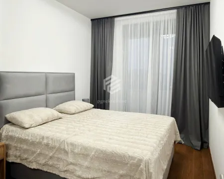 Namještena spavaća soba sa bračnim krevetom, sivim zavjesama i televizorom na zidu. - image 6