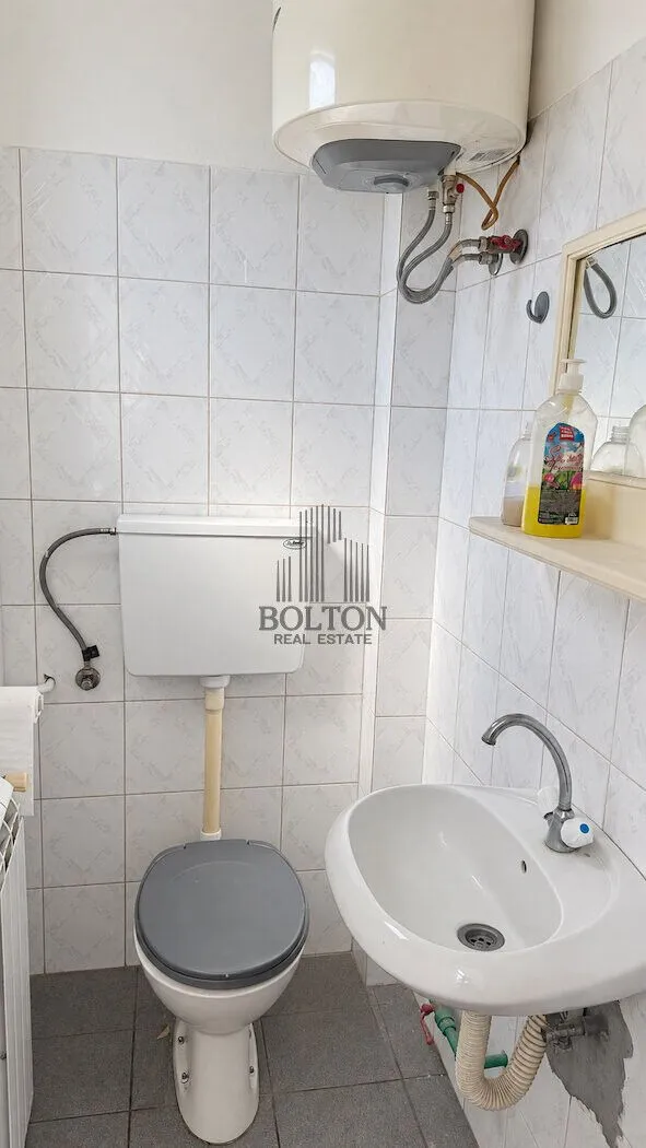Smaller bathroom with a toilet, washbasin, and water heater.