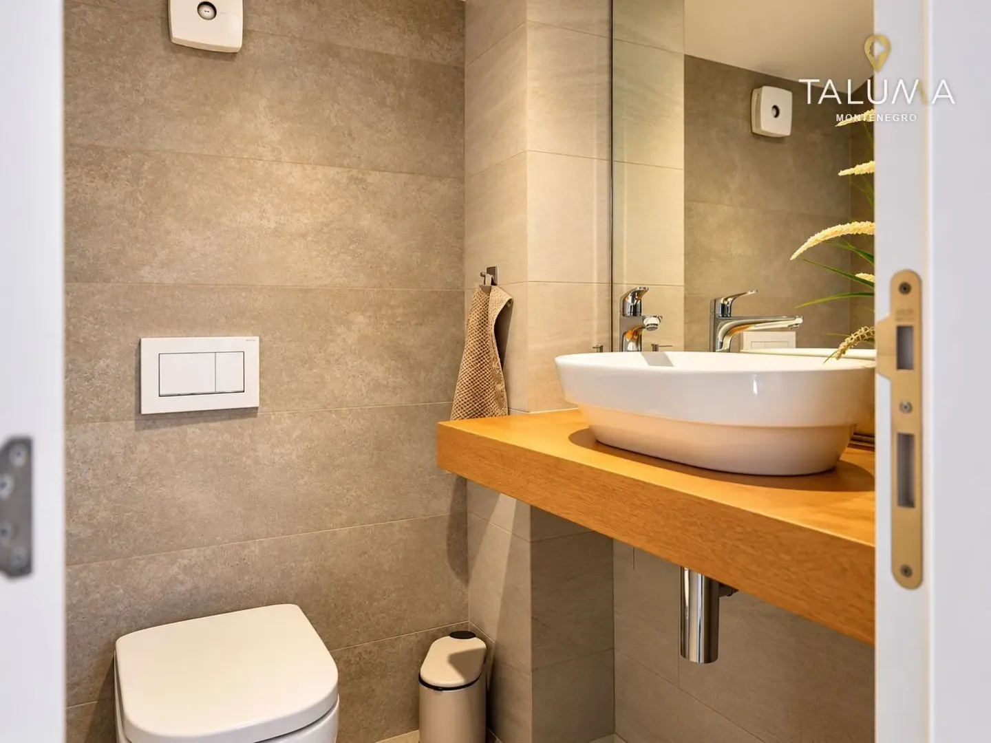 Modern bathroom with a sink on a wooden shelf and a toilet.