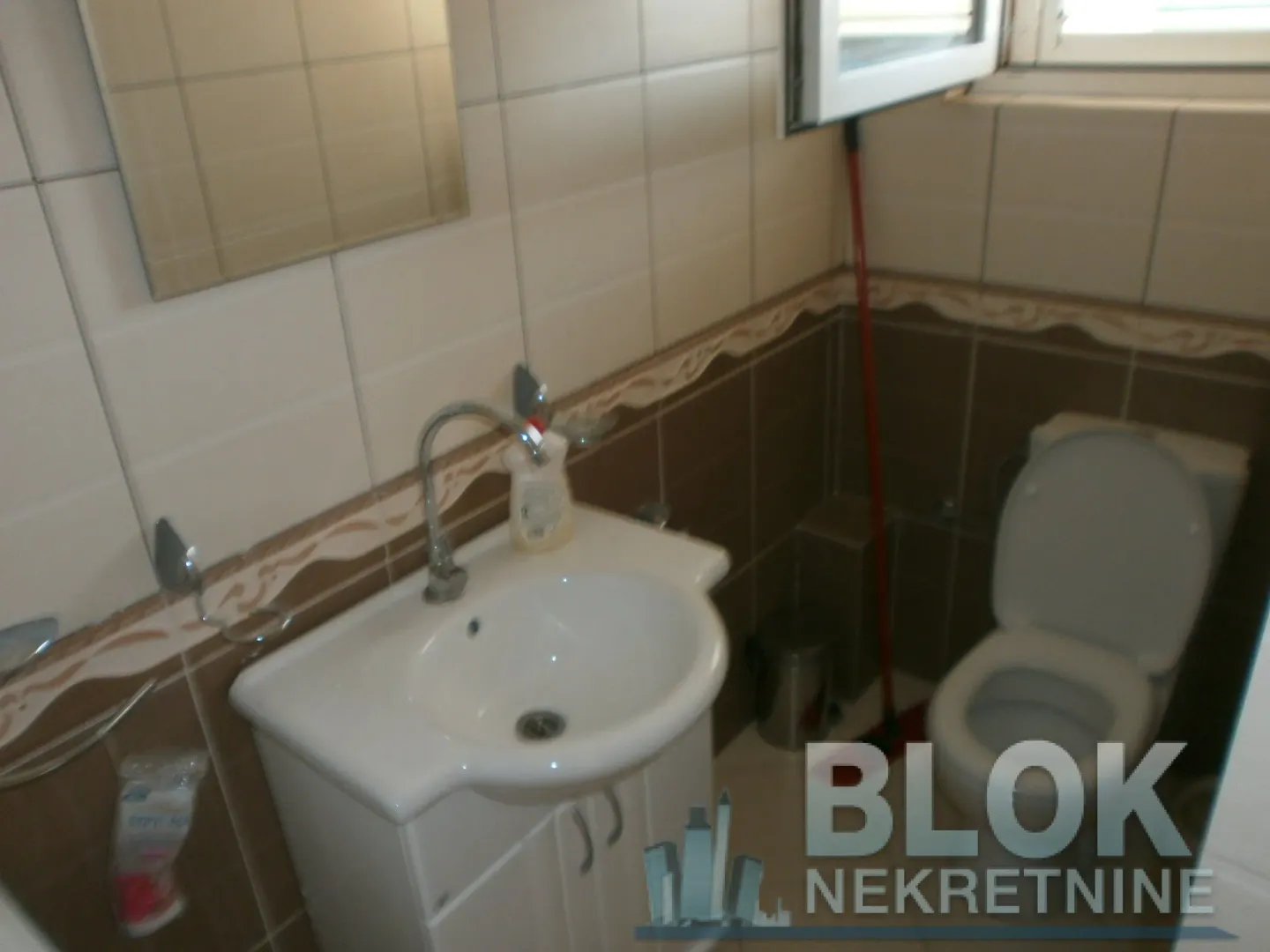 Small bathroom with a washbasin, mirror, and toilet bowl.