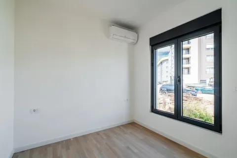 Prazna soba sa bijelim zidovima, drvenim podom, klima uređajem i prozorom. - image 5