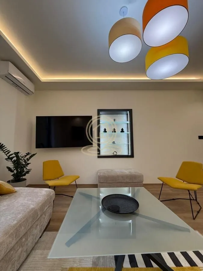 Dnevna soba sa garniturom, stočićem i modernim osvetljenjem.