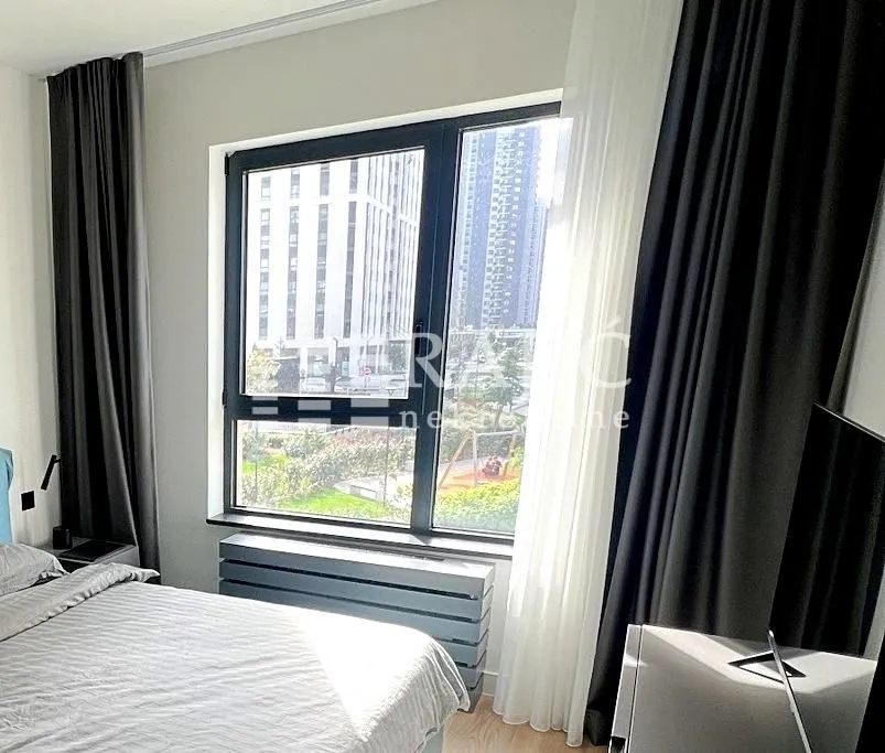 A bedroom with a double bed, a large window, and a TV.
