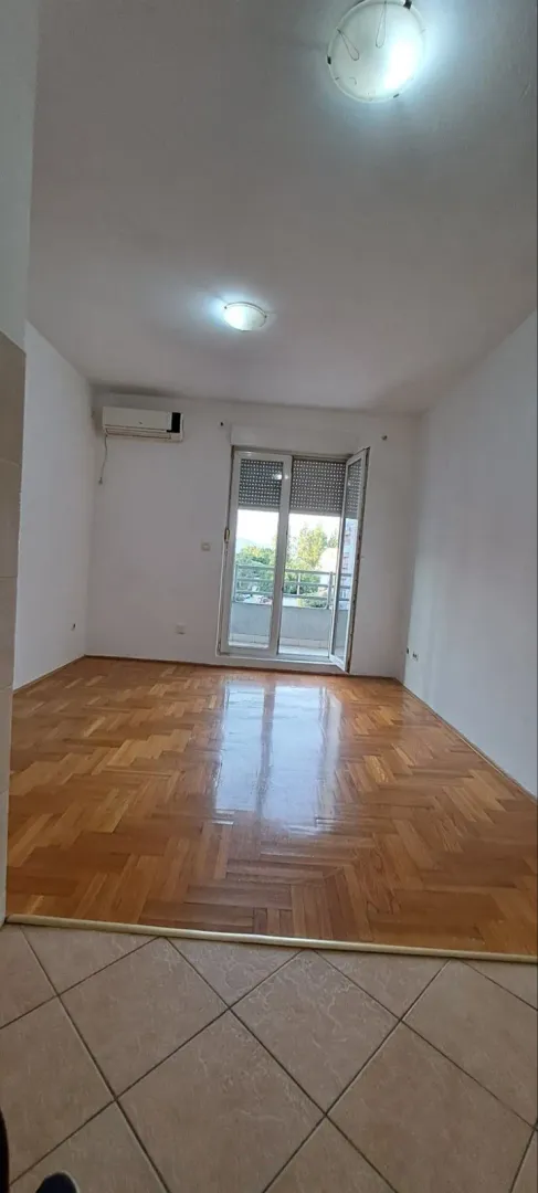 Prazna soba sa parketom i izlazom na terasu.