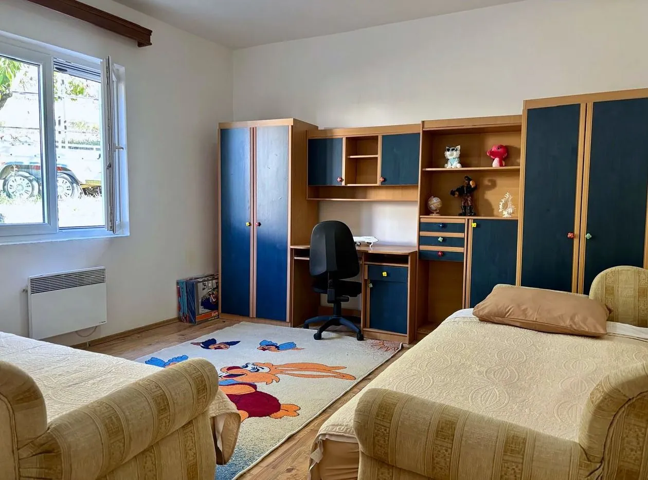 Children's bedroom with two beds, a desk, and wardrobes.