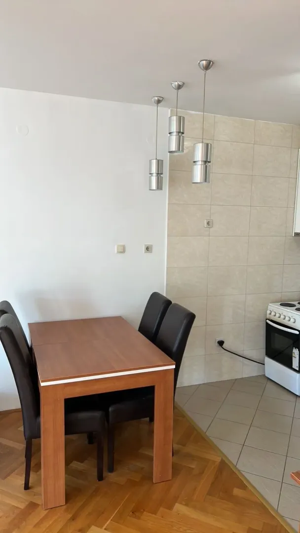 Trpezarijski sto sa stolicama u blizini kuhinjskog dijela.