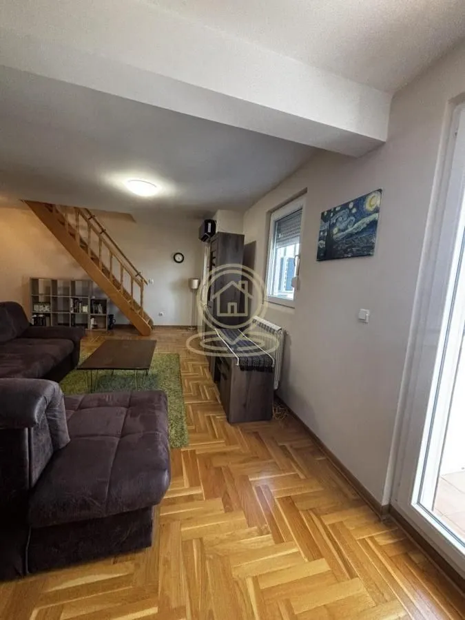 Living room with sofa set, wooden stairs and parquet flooring.