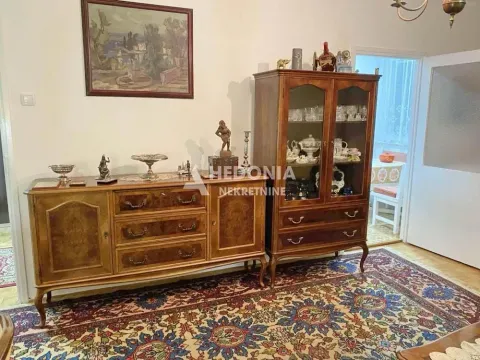Dnevna soba sa drvenim komadima nameštaja i tepihom na podu. - image 5
