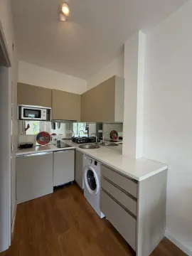 Compact equipped kitchen with white goods and wooden flooring. - image 4