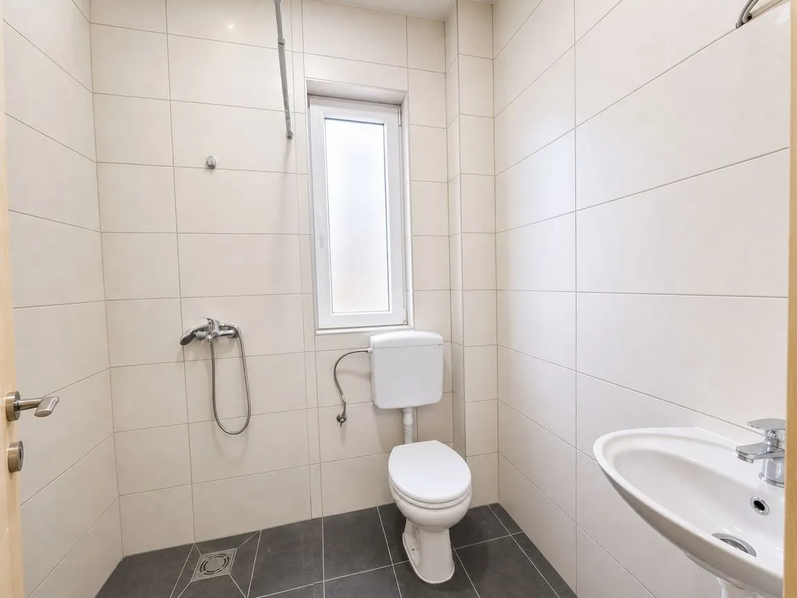 Manje kupatilo sa tuš kabinom, WC šoljom i umivaonikom.