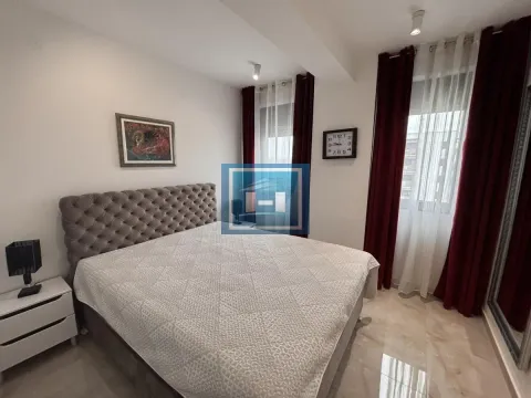 Prostrana spavaća soba sa bračnim krevetom, belim noćnim ormarićem i tamnocrvenim zavesama. - image 8