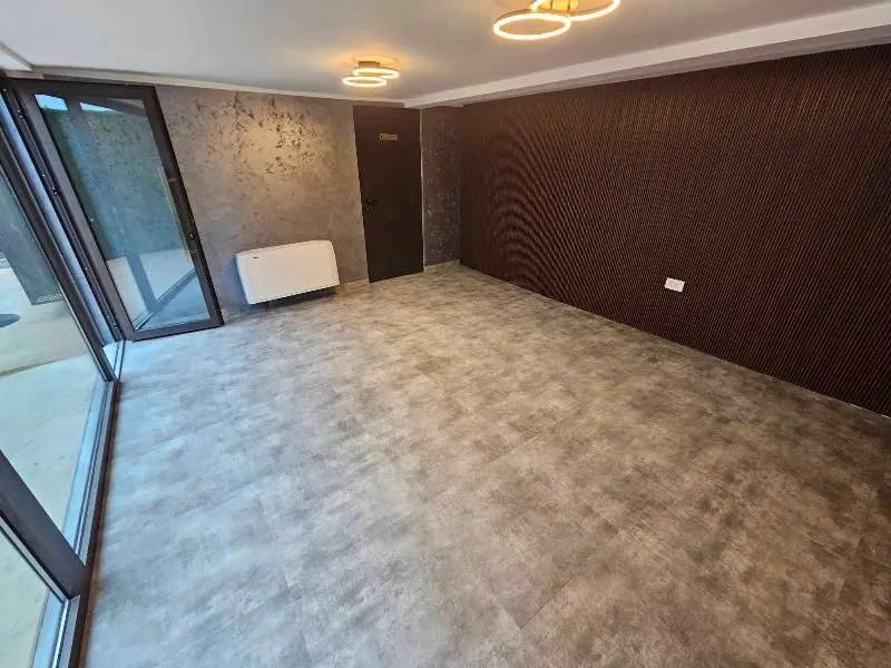 Empty room with a dark accent wall and glass doors leading to the terrace.