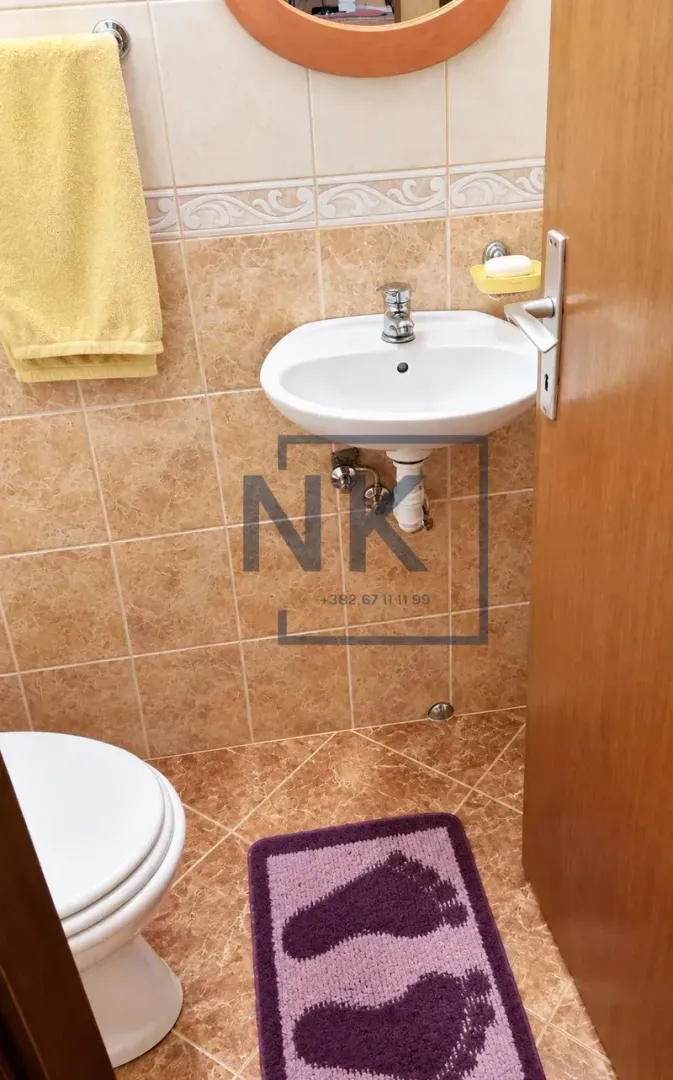 Smaller bathroom with a washbasin, toilet bowl, and beige tiles.