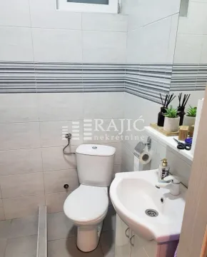 Small bathroom with a shower cabin, washbasin, and toilet. - image 7
