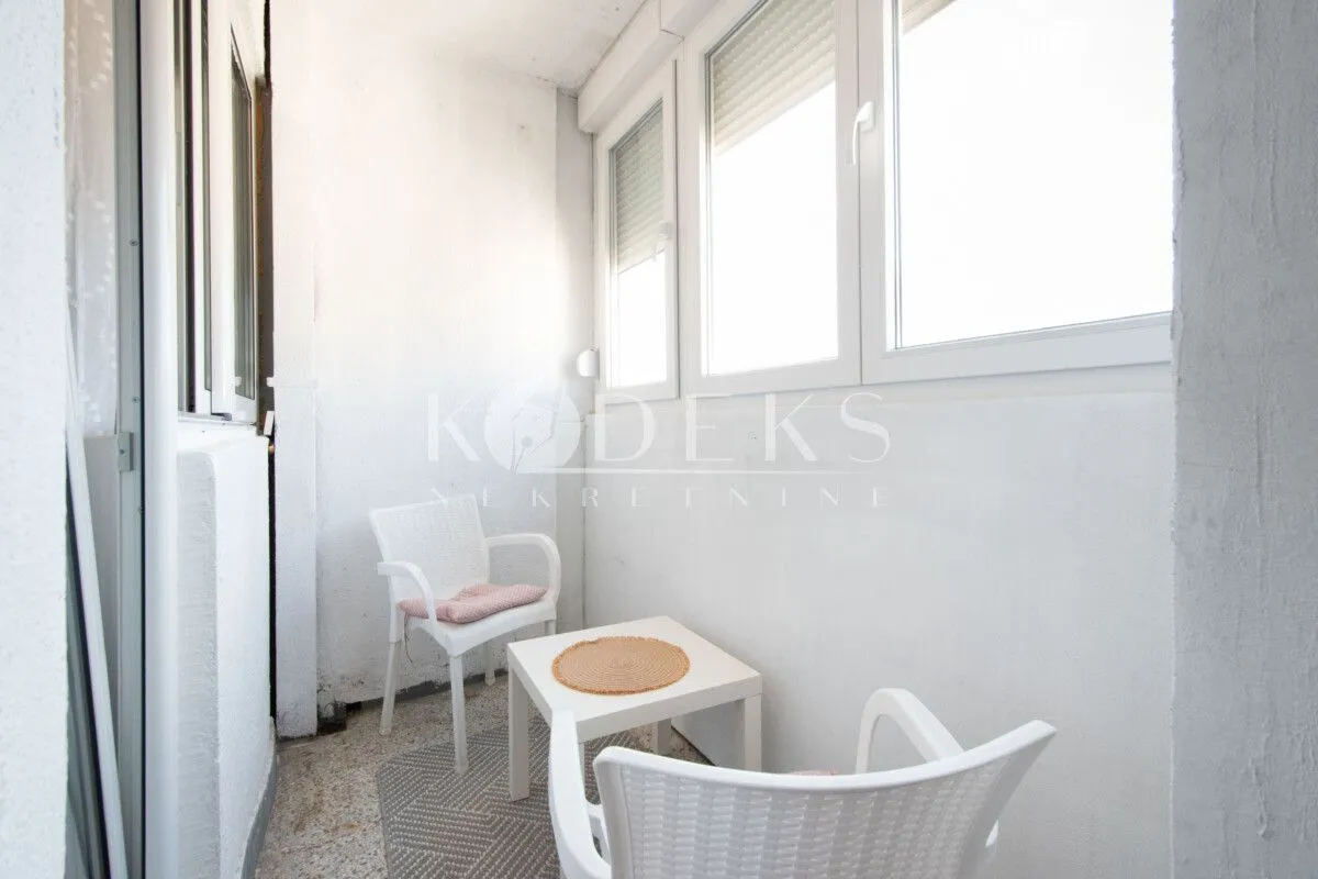 Enclosed balcony with a white table and two chairs.