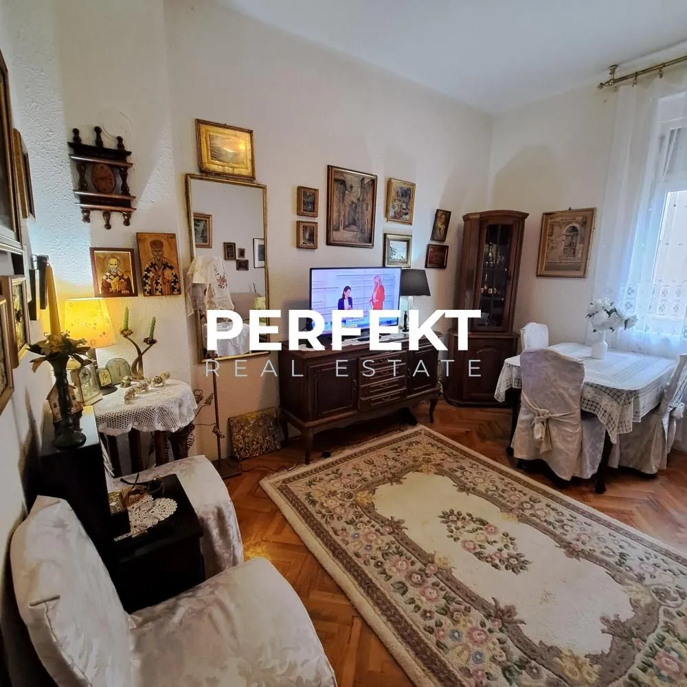 Tradicionalno opremljena dnevna soba sa garniturom za sedenje i trpezarijskim stolom.