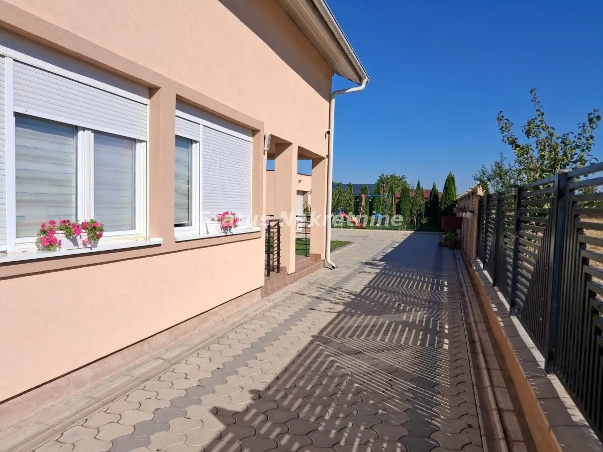 Popločano dvorište i bočna strana kuće sa ogradom.
