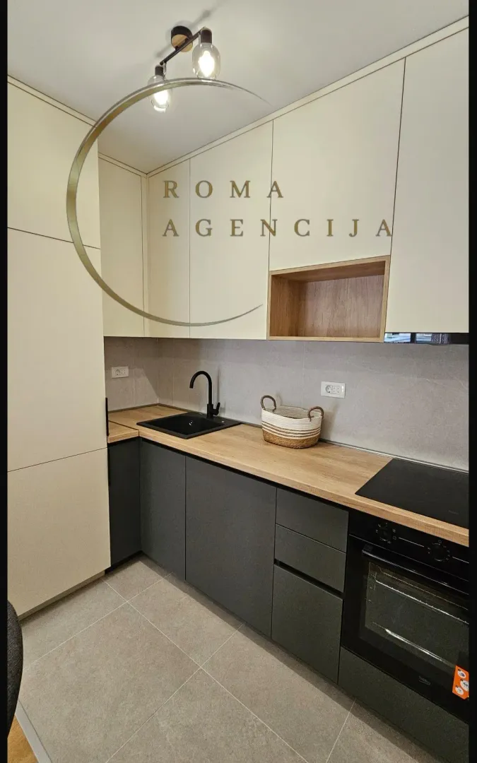 Moderna kuhinja sa tamnim radnim elementima i svijetlim gornjim ormarićima.