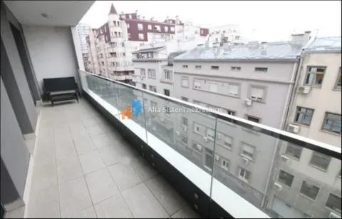 Dugačak popločani balkon sa staklenom ogradom i pogledom na okolne zgrade. - image 18