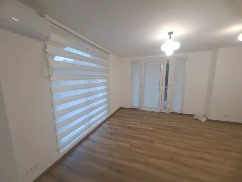 Empty room with white walls, wooden flooring, and windows with blinds. - image 7