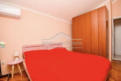 A simple bedroom with a double bed, a wooden wardrobe, and an air conditioning unit. - image 7