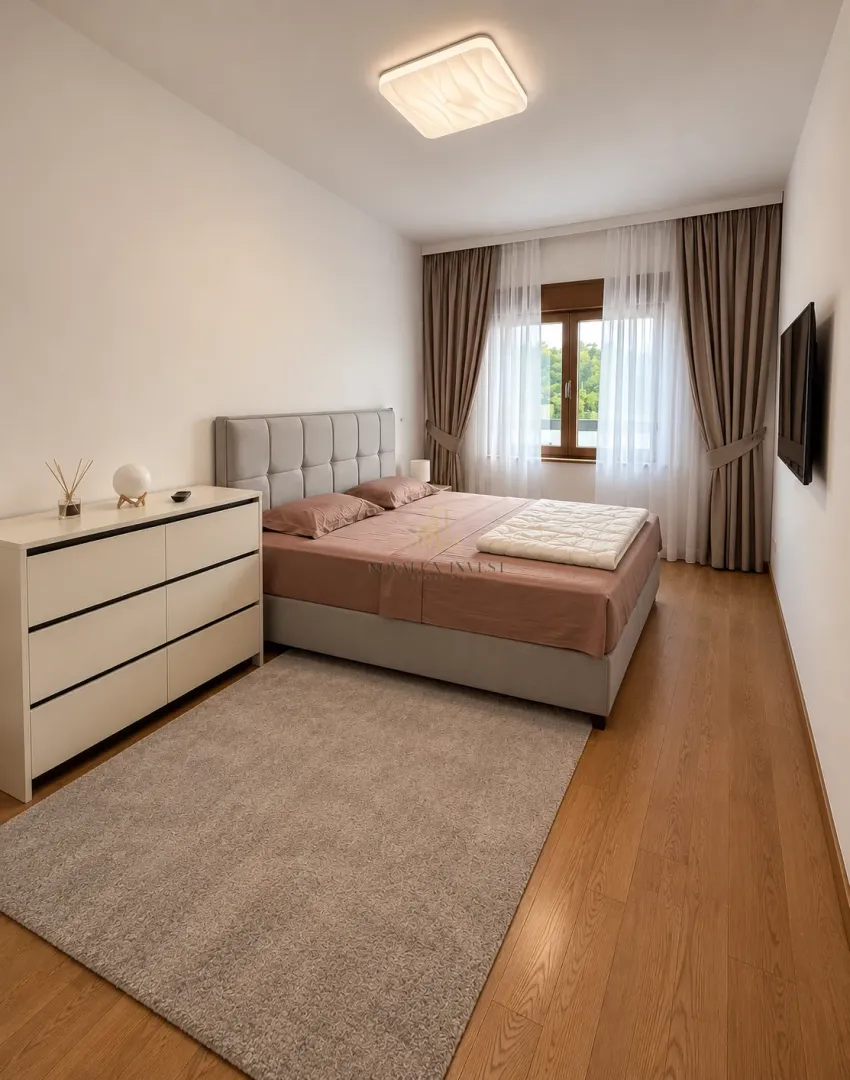 Furnished bedroom with a double bed, dresser, and wall-mounted TV.