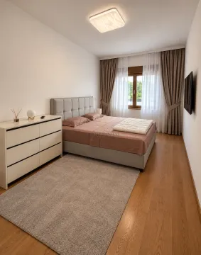 Furnished bedroom with a double bed, dresser, and wall-mounted TV. - image 7