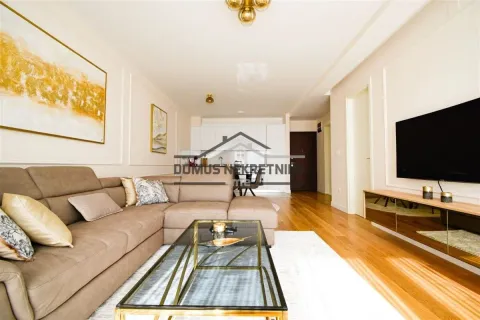 Living room with a sofa, coffee table, and a view towards the kitchen and entrance door. - image 4